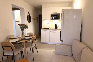 une cuisine et une salle à manger avec une table et un réfrigérateur dans l'établissement Corsica Bellezza - T2 avec piscine & plage privée, à Pianottoli-Caldarello