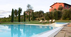 a swimming pool with chairs and a house in the background at Agriturismo Corte in Poggio in Stabbia +39 photos