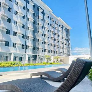 a apartment building with two chairs and a swimming pool at Staycation by Mailine in Manila