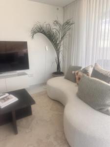 salon z białą kanapą i telewizorem w obiekcie Marbella GOLF & SEA LODGE w mieście Estepona