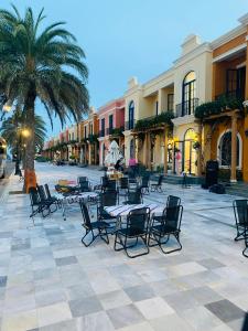 a courtyard with tables and chairs and palm trees at NAMstay Villa - Novaworld Phan Thiet in Bình Tú