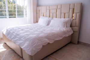 a bedroom with a large white bed with a large window at Bellissima Homes in Kericho