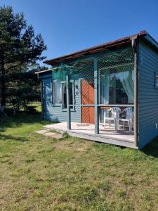 a blue shed with two white chairs on a porch at Camping Zvejnieksēta in Pāvilosta