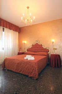 a bedroom with a bed with red sheets and a chandelier at B&B Rialto Dream in Venice
