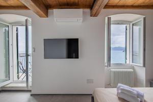 a bedroom with a flat screen tv and windows at Eldorado,Romantic Seafront Getaway in Manarola