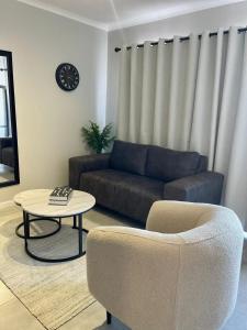 Una sala de estar con un sofá, una mesa y una silla. en The Urban Edge, en Ciudad del Cabo