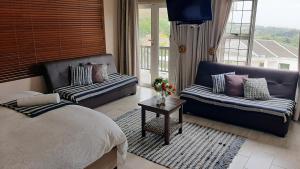 a bedroom with a bed and a couch and a table at Bella Vista Guest House La Lucia Umhlanga in Durban +34 photos
