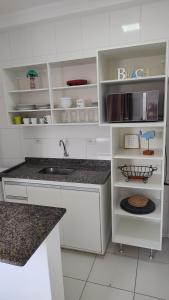 a kitchen with white cabinets and a sink at Itaguá - 1 quadra da praia, 2 quartos, 2 banheiros, acomoda 5 pessoas in Ubatuba