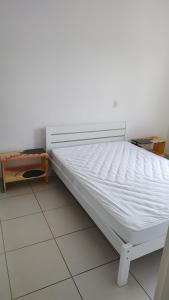 a bed in a room with a white mattress at Itaguá - 1 quadra da praia, 2 quartos, 2 banheiros, acomoda 5 pessoas in Ubatuba