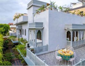 ein weißes Haus mit einem Tisch und Stühlen auf einem Balkon in der Unterkunft Camellia Heritage Homestay in Jaipur