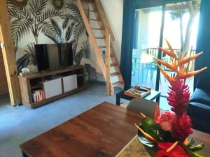 a living room with a table with a television and a staircase at L'Escale des Bambous in Saint-Paul