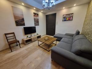 a living room with a gray couch and a tv at unique 2bedroom at abdoun 006 in Amman