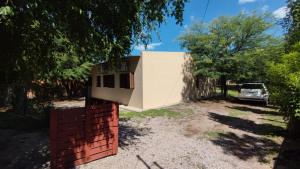 a house with a white wall and a car at Finca con pileta Lasmaria in Santiago del Estero