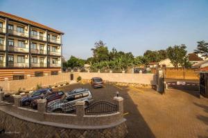 deux voitures garées sur un parking devant un immeuble dans l'établissement Inophine Boutique Hotel Entebbe, à Entebbe