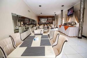 un restaurant avec une table, des chaises et un comptoir dans l'établissement Inophine Boutique Hotel Entebbe, à Entebbe