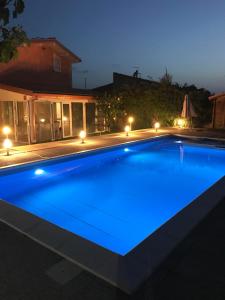 a swimming pool lit up at night with lights at Lovely Independent Villa in Plaia Grande