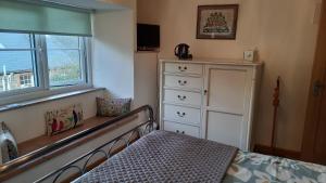 a bedroom with a bed and a dresser and a window at 2 Mill Cottages in Cornworthy