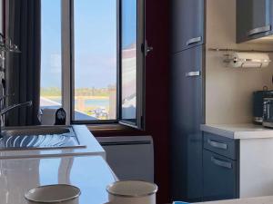 a kitchen with a sink and two stools in front of a window at Studio Lumineux Proche Plage et Commerces – Tout Équipé, Parking Gratuit - FR-1-542-66 in Trégastel