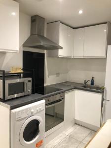 a kitchen with a washing machine and a microwave at Hendon Basement Studio in Hendon