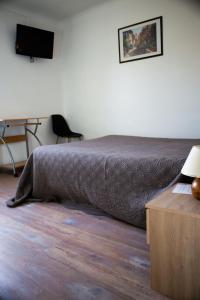 a bedroom with a bed and a desk and a television at Auberge le Cévenol in La Cavalerie