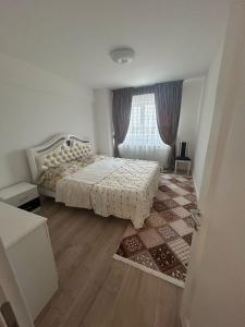 a white bedroom with a bed and a window at Abel 24 Residence in Bacău