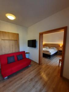 a living room with a red couch and a bed at Pension Alter Wirt in Enkering