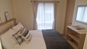 een slaapkamer met een bed met kussens en een raam bij Coastal Retreat Lodge in Morecambe