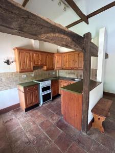 a kitchen with wooden cabinets and a stove top oven at Captains Cottage Dover in Wootton