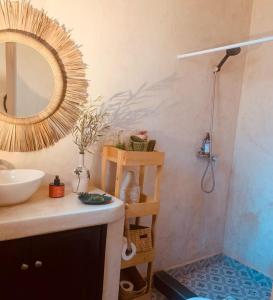 a bathroom with a sink and a shower with a mirror at Maison du soleil in Ghazoua
