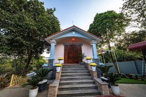 a small house with stairs leading to a wooden door at Phương Nam Garden in Ba Vì