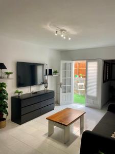 Una sala de estar con televisión y una mesa de café. en Helen House, en Caleta de Fuste