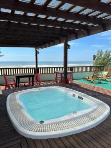 a hot tub on a deck with the ocean in the background at Residencial Veleiros Do Mar in Capão da Canoa
