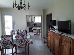 a living room with a television and a dining room at Le cerisier in Millau