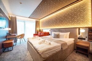 a hotel room with a large bed and a desk at Bordűr Wellness Hotel Superior és Szőnyegmúzeum in Békésszentandrás +144 photos