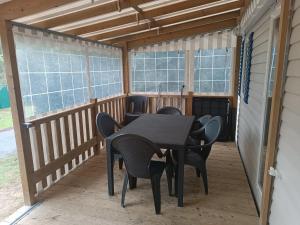 莱马特Mobil Home 40m2, Bonne Anse Siblu 4 étoiles的窗户门廊上的桌椅