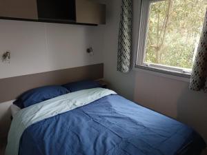莱马特Mobil Home 40m2, Bonne Anse Siblu 4 étoiles的卧室里有一张床，床铺是蓝色的，还有一扇窗户