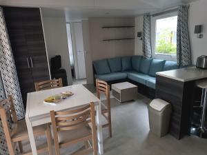 莱马特Mobil Home 40m2, Bonne Anse Siblu 4 étoiles的客厅里有一张蓝色的沙发、一张桌子和几把椅子