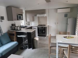 莱马特Mobil Home 40m2, Bonne Anse Siblu 4 étoiles的配有桌子和沙发的厨房和客厅