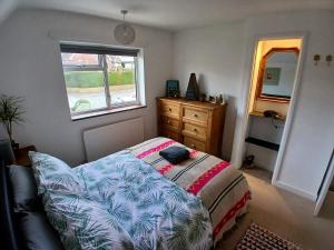 a bedroom with a bed and a dresser and a window at Down by the Riverside in Blandford Forum