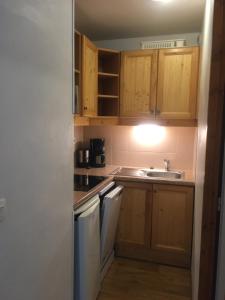 a small kitchen with wooden cabinets and a sink at Les orres 1800 appartement 4 personnes au pied des pistes in Les Orres