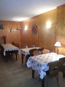jadalnia ze stołami i krzesłami oraz drewnianymi ścianami w obiekcie Auberge du Col de Neronne w mieście Le Falgoux