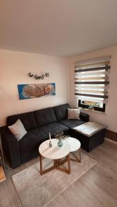 un soggiorno con un divano nero e un tavolo di Ferienhaus Roßbachtal a Biberschlag