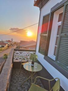 a table and chairs on a balcony with the sunset at Casa Pereira 1 in Ponta do Pargo