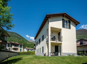 a white building with a balcony and mountains in the background at My Holidays New Eden Mansarda in Domaso