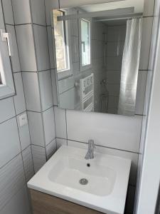 un bagno bianco con lavandino e specchio di Maison avec vue mer à Omaha Beach - idéal familles a Saint-Laurent-sur-Mer Altre 7 foto