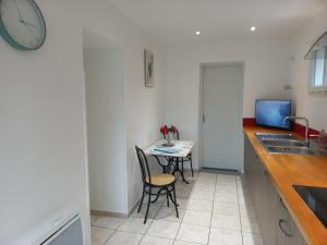 a kitchen with a table and chairs and a clock at Appartement avec jardin in Adé +2 photos