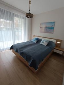 a bedroom with a large bed in a room with windows at Apartament Blue Haven in Pogorzelica +14 photos