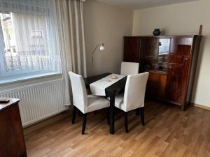 a dining room table with white chairs and a window at Ferienwohnung Nachtigall in Burg +12 photos