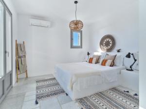 una camera da letto bianca con un letto e un lampadario di IOKASTI LUXURY VILA with private pool & sea views-12 guests a Drios