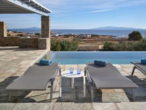 un patio con 2 sedie e un tavolo accanto alla piscina di IOKASTI LUXURY VILA with private pool & sea views-12 guests a Drios